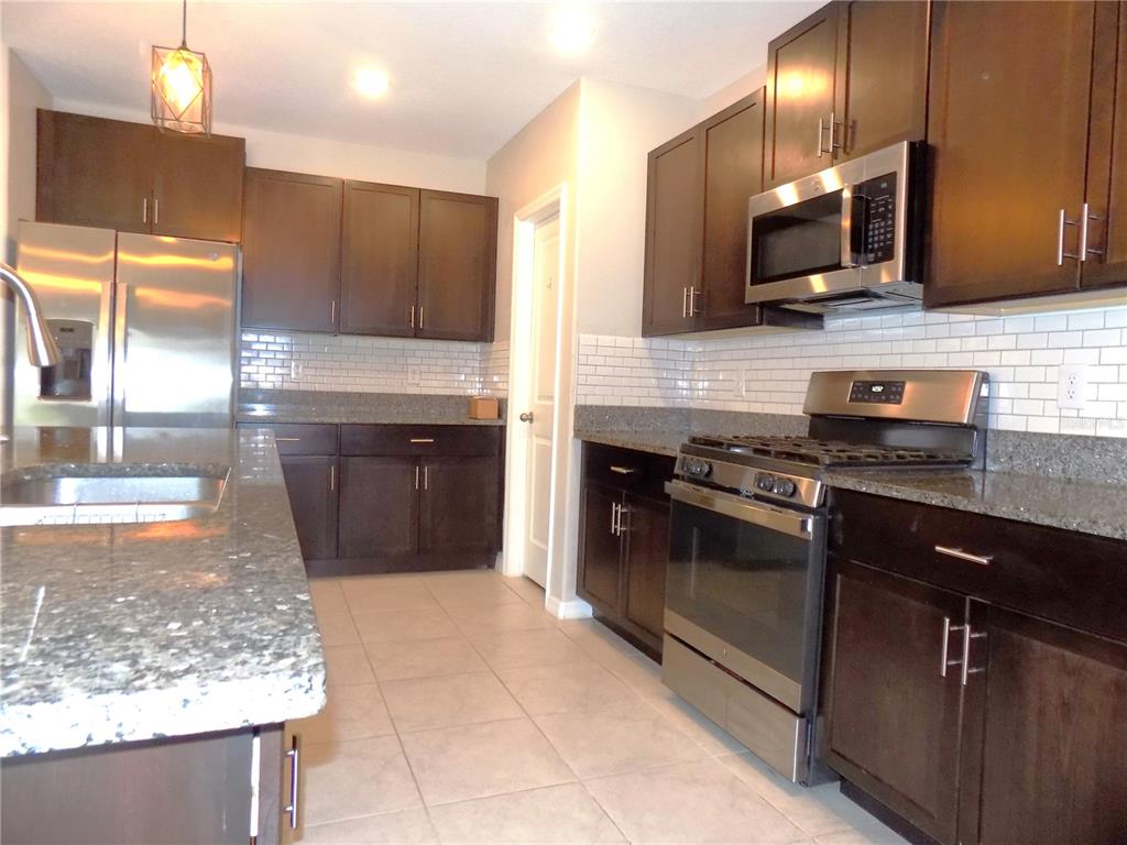 9411 Lemon Drop Loop Sun City Center, FL 33573 - Photo 11 of 47 a kitchen with stainless steel appliances granite countertop a sink stove and microwave