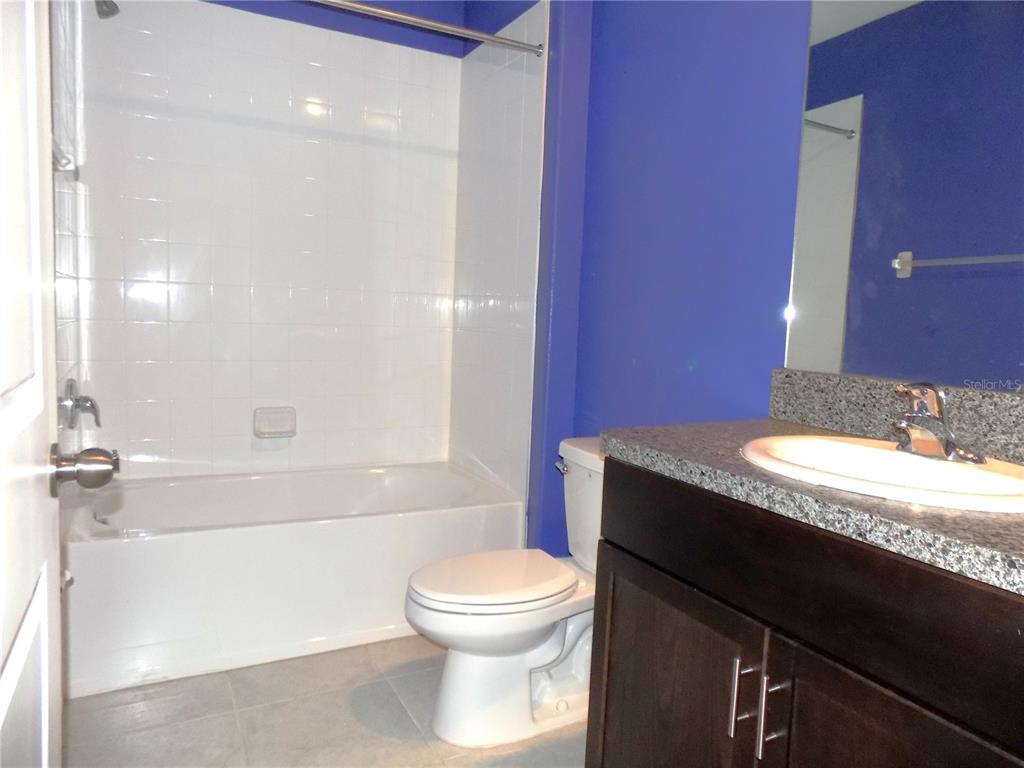 9411 Lemon Drop Loop Sun City Center, FL 33573 - Photo 17 of 47 a bathroom with a granite countertop sink toilet a mirror and bathtub