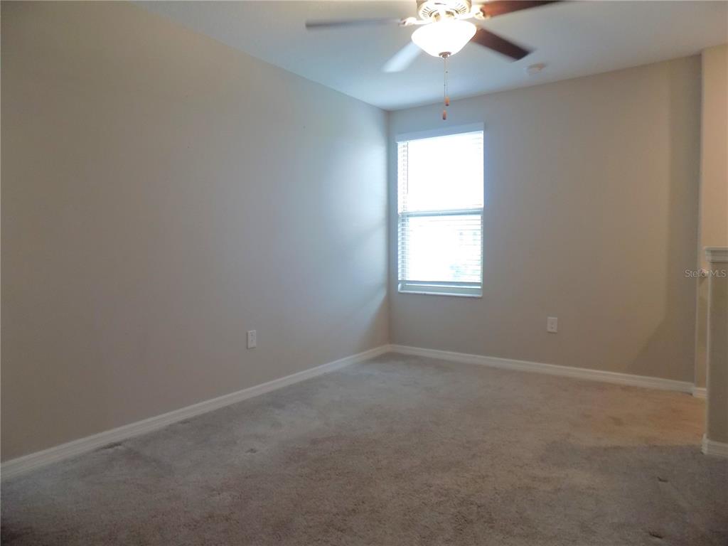9411 Lemon Drop Loop Sun City Center, FL 33573 - Photo 21 of 47 an empty room with a window and a chandelier fan