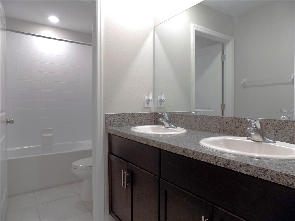 9411 Lemon Drop Loop Sun City Center, FL 33573 - Photo 36 of 47 a bathroom with a granite countertop sink a toilet and shower