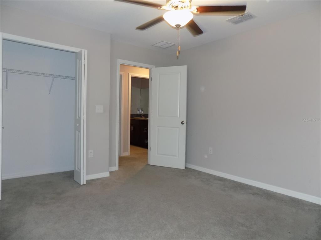 9411 Lemon Drop Loop Sun City Center, FL 33573 - Photo 37 of 47 an empty room with a chandelier fan and a bathroom
