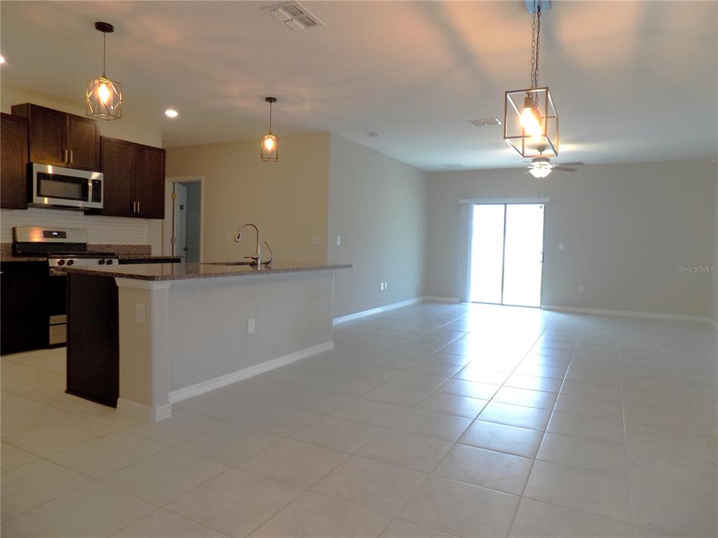 9411 Lemon Drop Loop Sun City Center, FL 33573 - Photo 7 of 47 a kitchen with stainless steel appliances granite countertop a sink a stove a refrigerator cabinets and a dining table