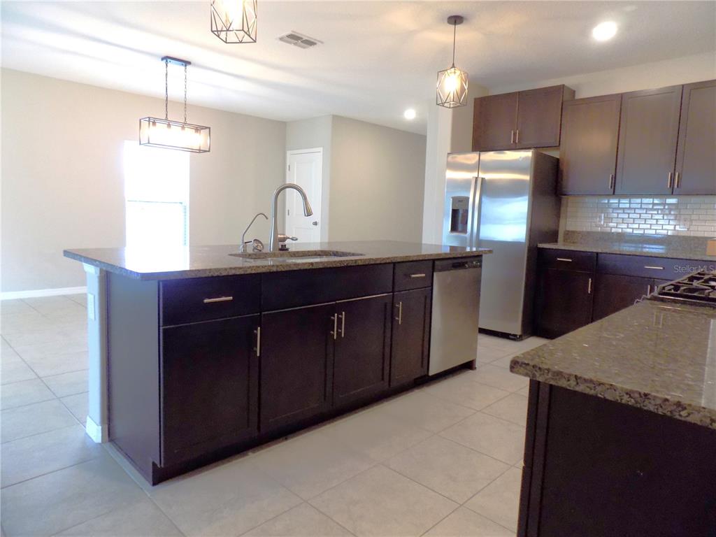 9411 Lemon Drop Loop Sun City Center, FL 33573 - Photo 8 of 47 a kitchen with kitchen island granite countertop a sink counter top space cabinets and appliances