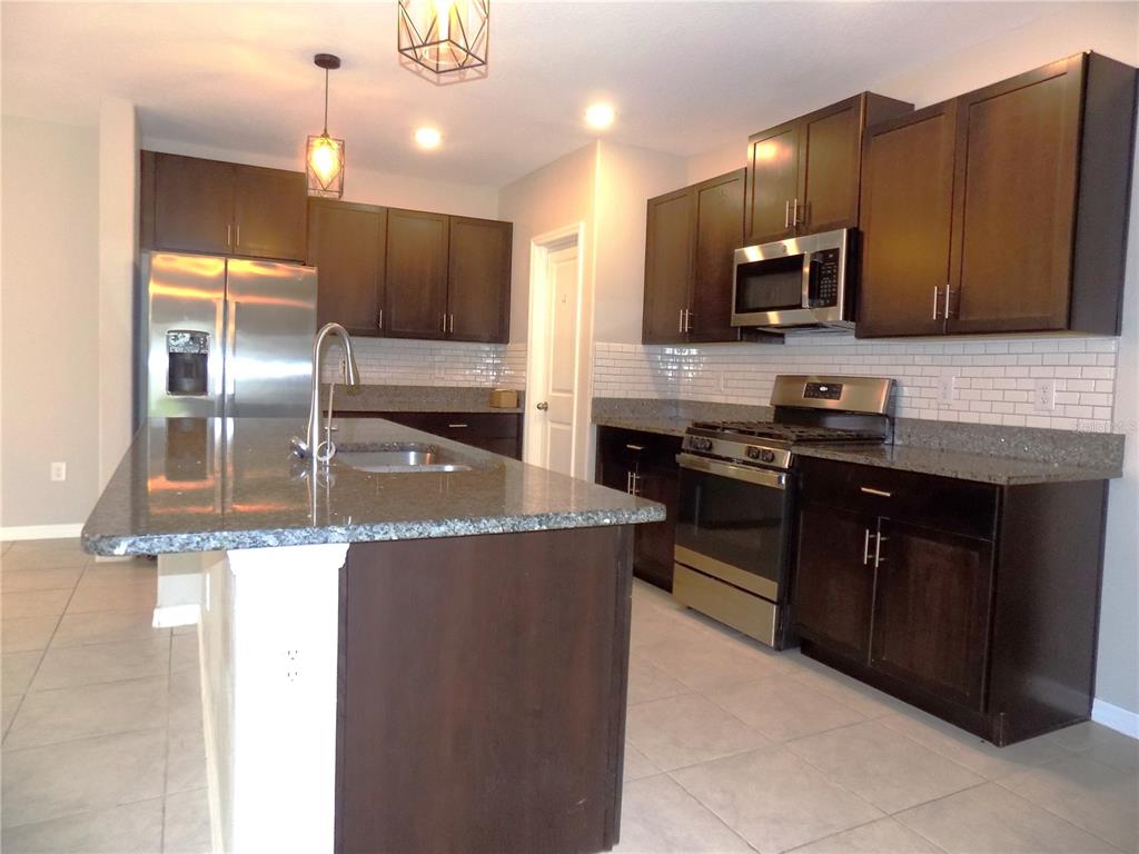 9411 Lemon Drop Loop Sun City Center, FL 33573 - Photo 9 of 47 a kitchen with stainless steel appliances granite countertop a sink a stove and cabinets
