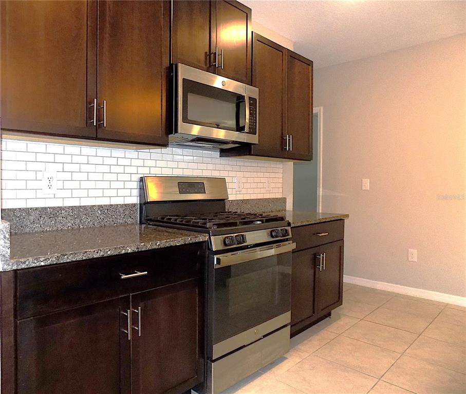 9411 Lemon Drop Loop Sun City Center, FL 33573 - Photo 10 of 47 a kitchen with granite countertop cabinets and steel stainless steel appliances