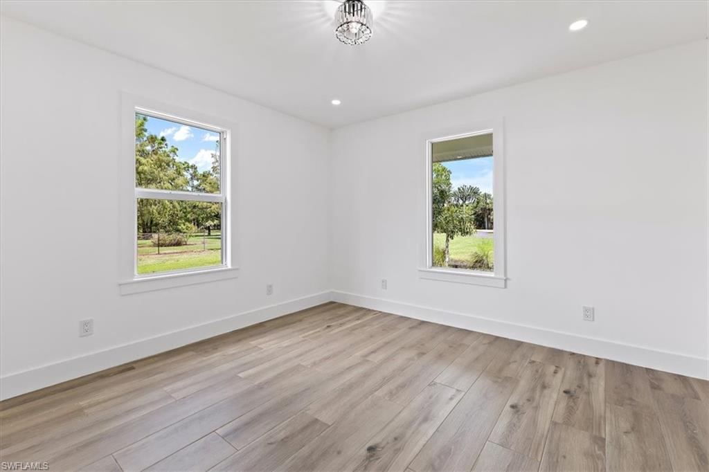 261 13th Street Southwest Naples, FL 34117 - Photo 13 of 35 Empty room featuring light wood-type flooring and an inviting chandelier