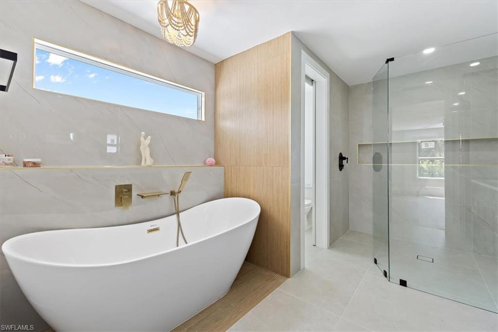 261 13th Street Southwest Naples, FL 34117 - Photo 25 of 35 Bathroom with tile walls, separate shower and tub, toilet, and tile patterned floors