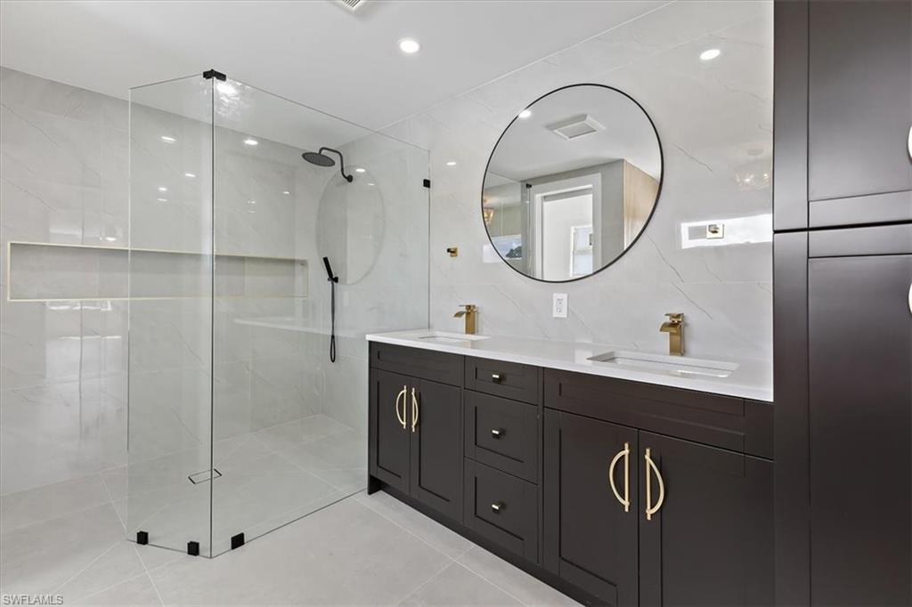 261 13th Street Southwest Naples, FL 34117 - Photo 26 of 35 Bathroom featuring tile patterned floors, vanity, tasteful backsplash, tiled shower, and tile walls