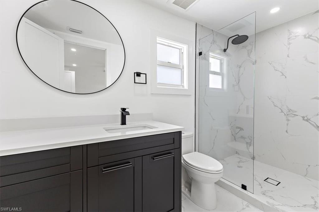 261 13th Street Southwest Naples, FL 34117 - Photo 29 of 35 Bathroom with tiled shower, vanity, and toilet