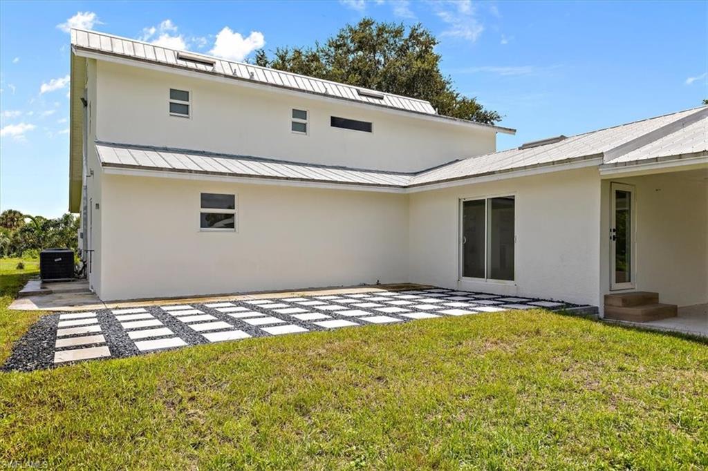 261 13th Street Southwest Naples, FL 34117 - Photo 31 of 35 Back of house with central AC, a lawn, and a patio area