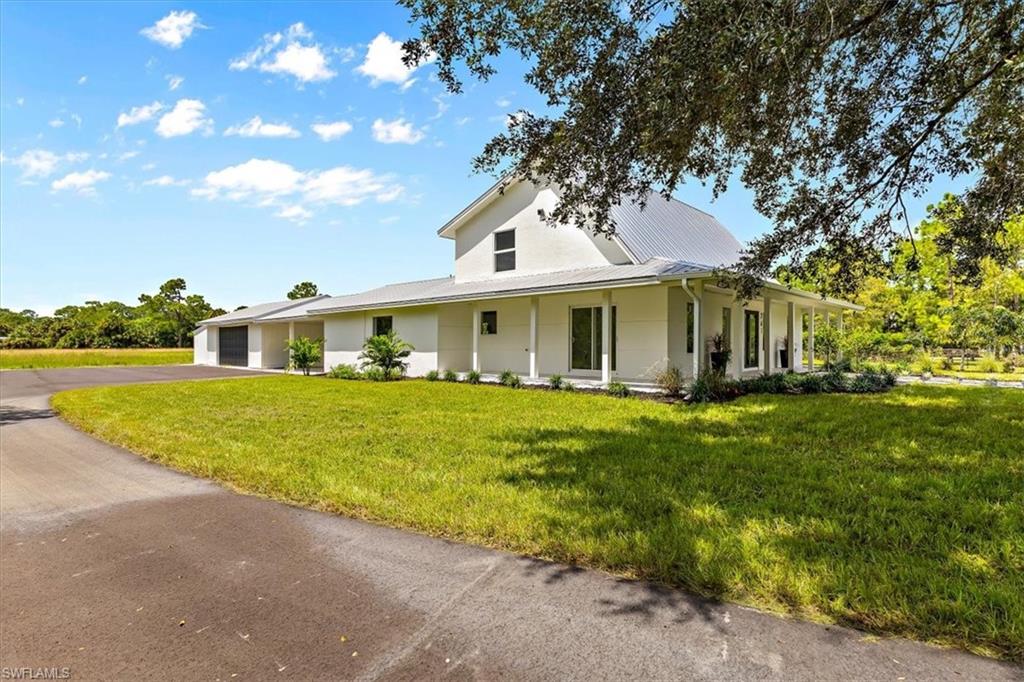 261 13th Street Southwest Naples, FL 34117 - Photo 4 of 35 Farmhouse-style home featuring covered porch, a front yard, and a garage