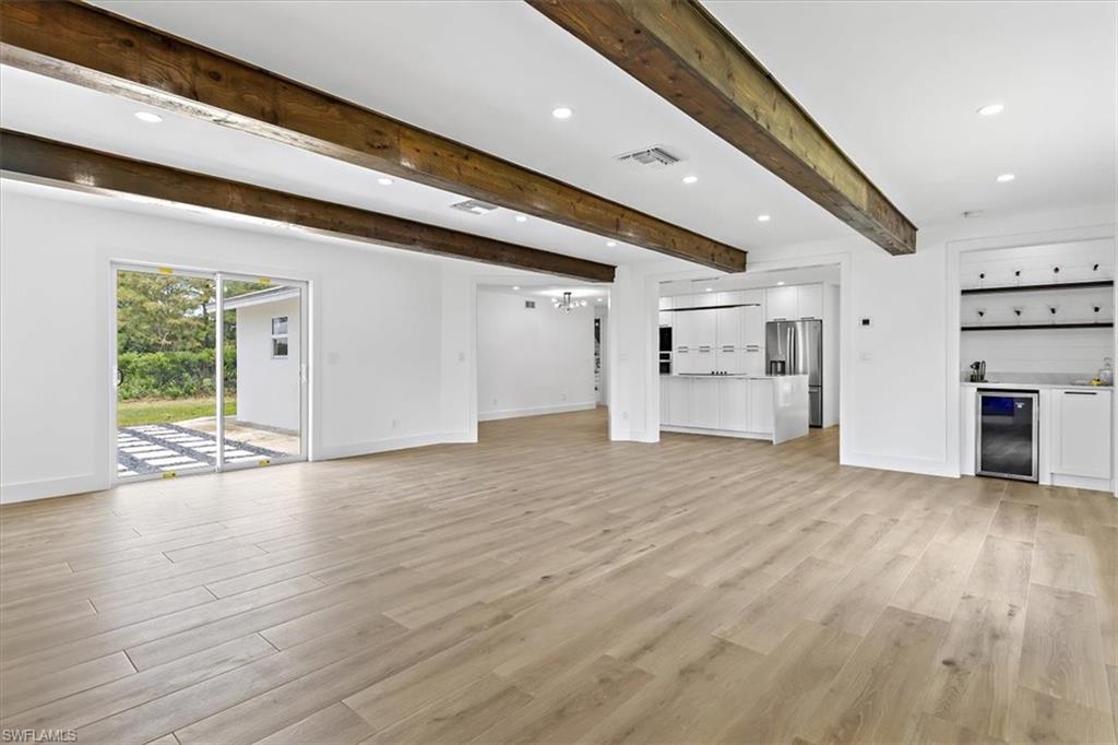 261 13th Street Southwest Naples, FL 34117 - Photo 6 of 35 Unfurnished living room with beverage cooler, beamed ceiling, and light hardwood / wood-style flooring