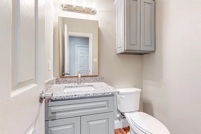 a bathroom with a granite countertop toilet sink and mirror