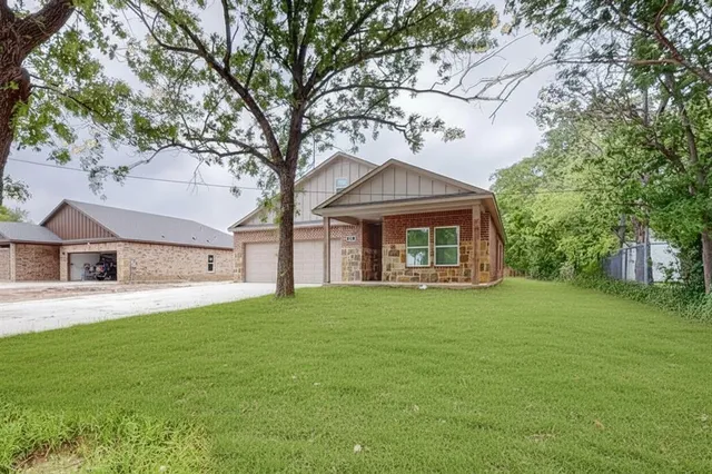 a front view of a house with a garden and trees