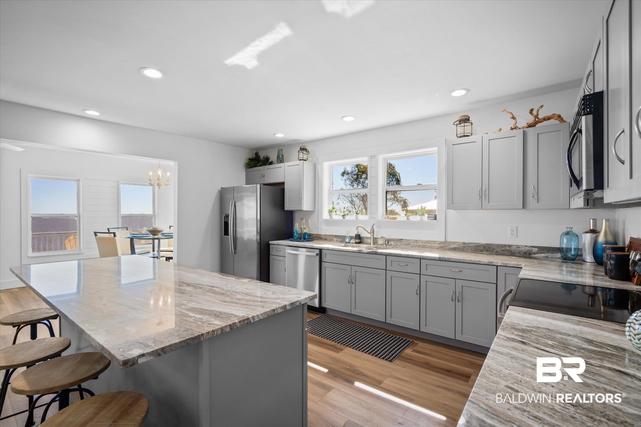 15111 Regus Road Coden, AL 36523 - Photo 6 of 35 Kitchen featuring gray cabinets, light stone countertops, a kitchen breakfast bar, light wood-style floors, and appliances with stainless steel finishes