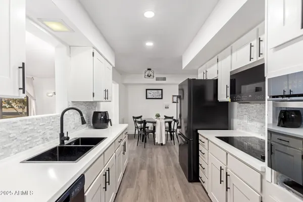 a kitchen with granite countertop a sink stainless steel appliances and white cabinets