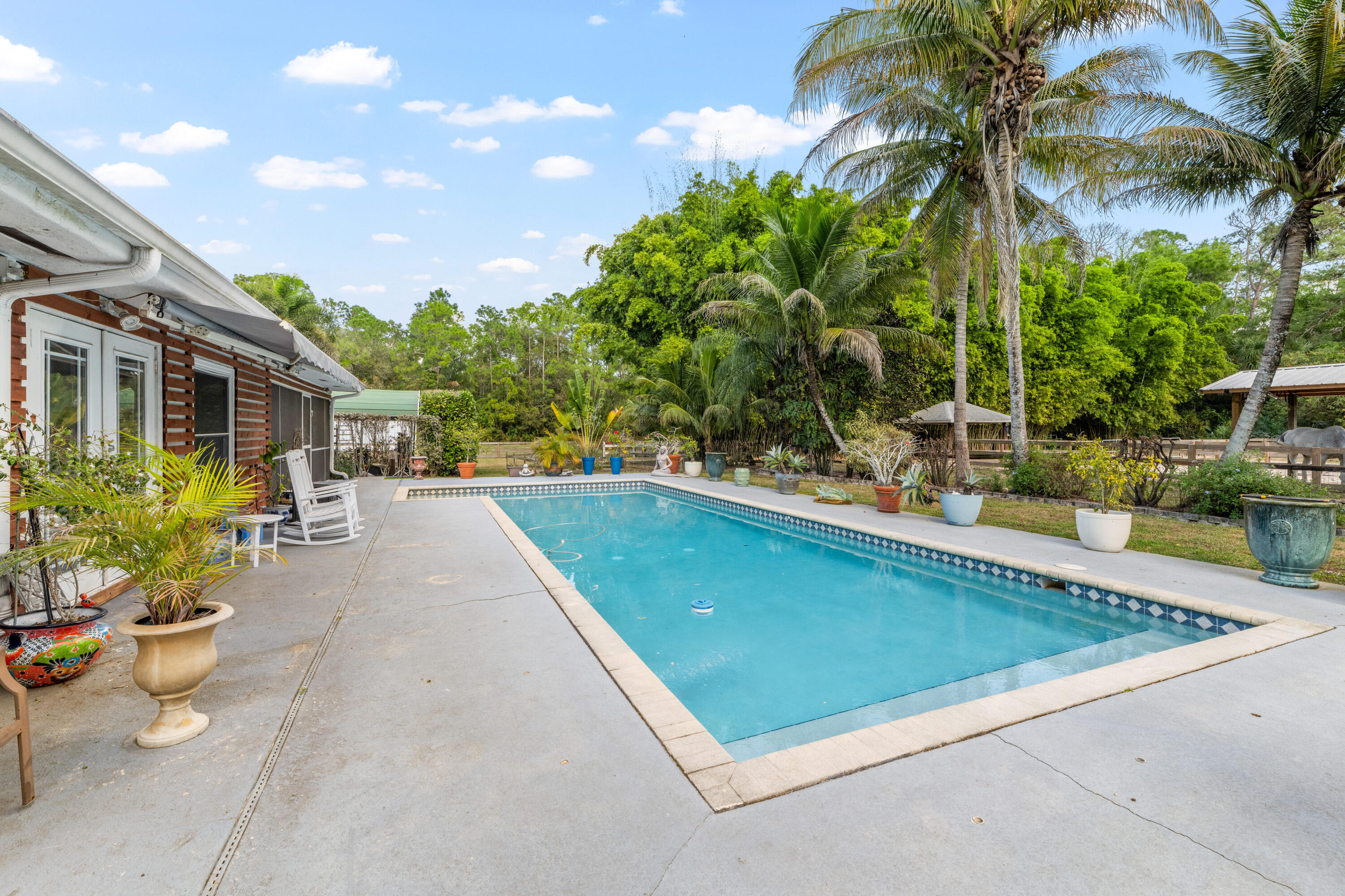 1068 D Road Loxahatchee, FL 33470 - Photo 66 of 73 a view of a swimming pool with a patio and a garden