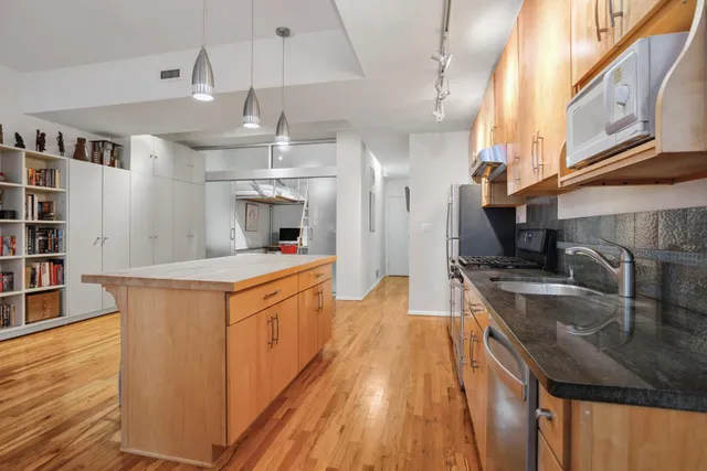 a kitchen with stainless steel appliances granite countertop a sink a stove and a wooden floors