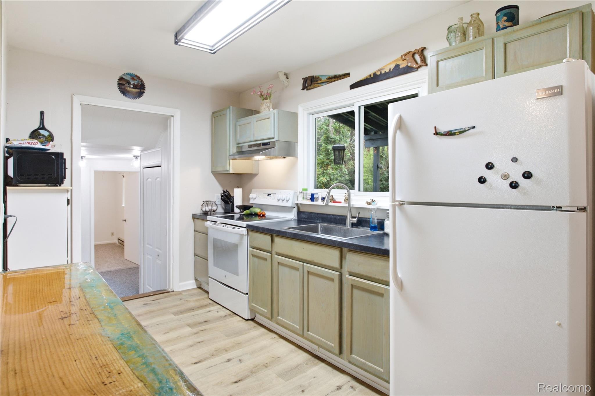 4945 Miller Road Ann Arbor, MI 48103 - Photo 11 of 42 Kitchen featuring wood-finish flooring, two-tone cabinetry, a dual-basin sink, and a built-in electric range with an overhead hood