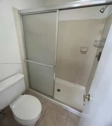 a white toilet sitting next to a shower