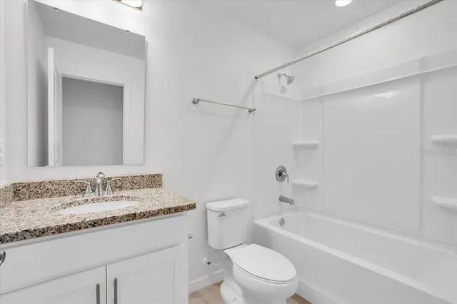 a bathroom with a granite countertop sink a toilet and a bathtub