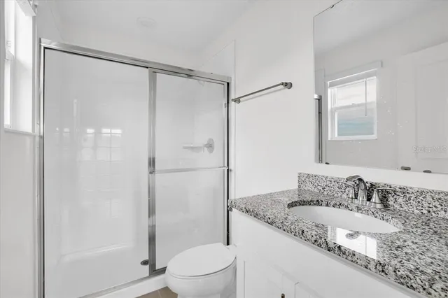 a bathroom with a granite countertop sink toilet and shower