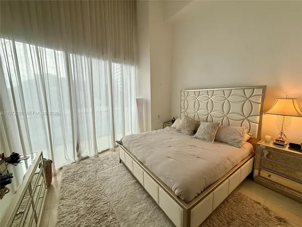 a large bed sitting in a bedroom next to a window