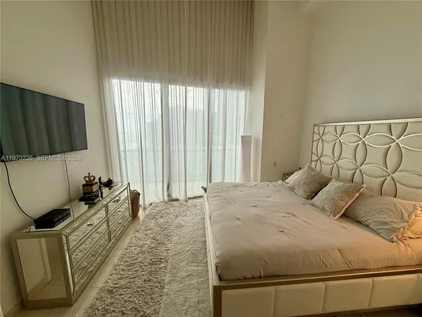 a bedroom with a bed a couch and a flat tv screen