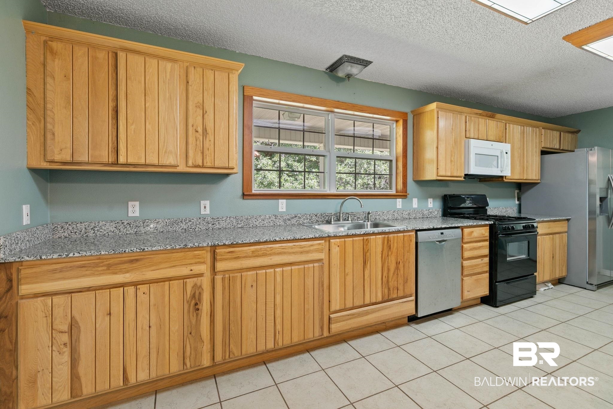 20219 Greek Cemetery Road Robertsdale, AL 36567 - Photo 18 of 41 Kitchen featuring wood cabinetry, light-toned countertops, and a window above the sink
