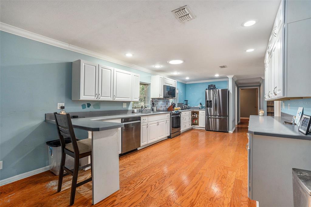 9738 Ray Street Hudson, FL 34669 - Photo 8 of 30 a kitchen with granite countertop a table chairs microwave and cabinets
