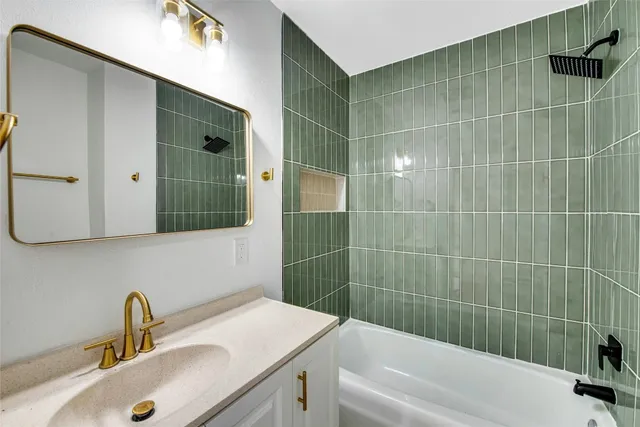 a bathroom with a sink and mirror with bathtub