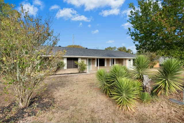 a front view of house with yard and trees around