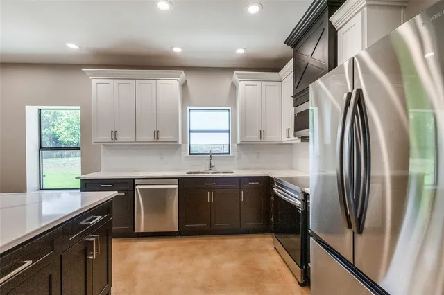 a kitchen with stainless steel appliances granite countertop a sink a stove a refrigerator and cabinets