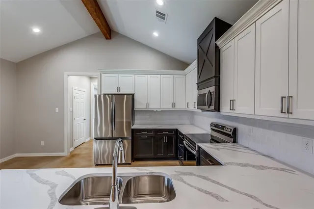 a kitchen with stainless steel appliances granite countertop a sink and a refrigerator