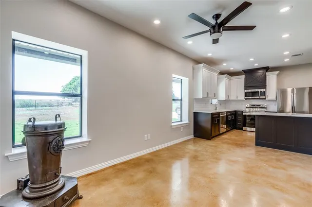 a view of a kitchen with kitchen island a counter top space a sink stainless steel appliances and a large window