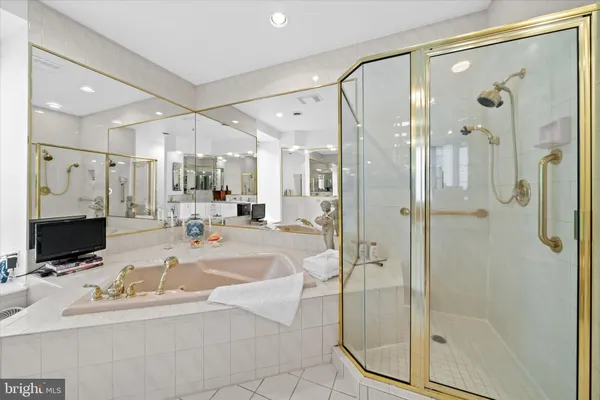 a bathroom with a tub a mirror and a shower