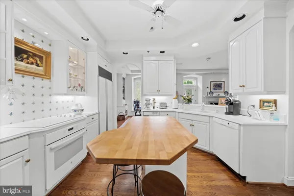 a kitchen with stainless steel appliances kitchen island granite countertop a sink a stove a refrigerator cabinets and a dining table with wooden floor