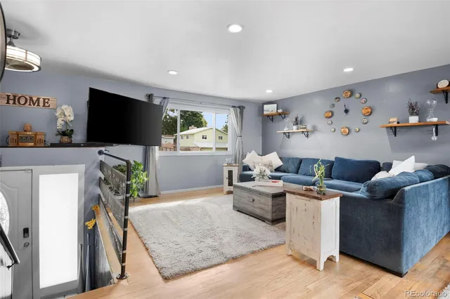 a living room with furniture a clock and a flat screen tv