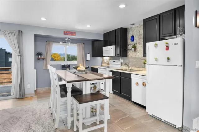 a kitchen with a dining table chairs refrigerator and microwave