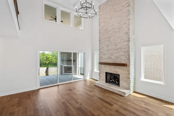 an empty room with windows fireplace and wooden floor