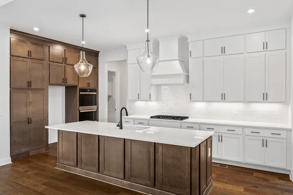 a kitchen that has a sink a center island stainless steel appliances and a chandelier