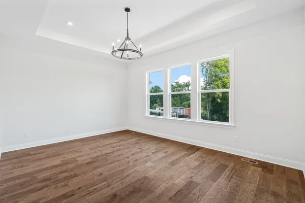 a view of an empty room with wooden floor and windows