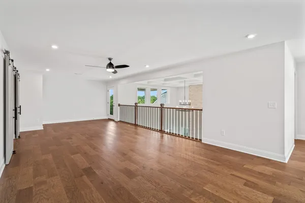 a view of an empty room with wooden floor and a ceiling fan