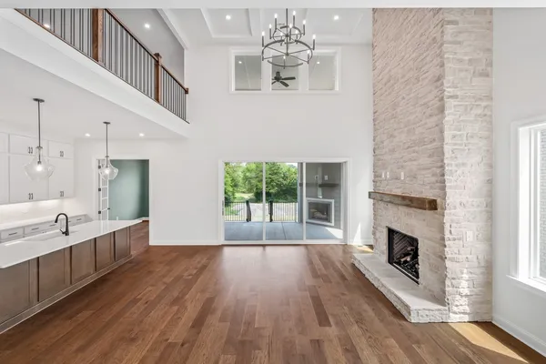 a view of an empty room with wooden floor fireplace and a window