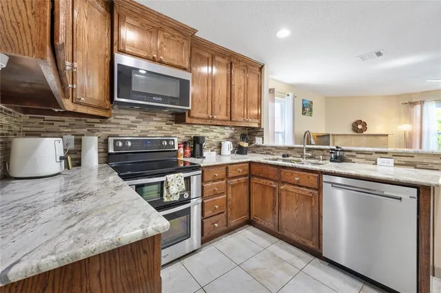 a kitchen with stainless steel appliances granite countertop wooden cabinets a stove top oven a sink and dishwasher