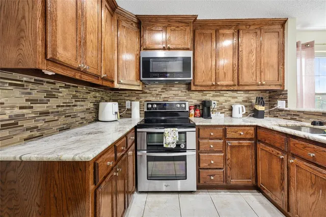 a kitchen with stainless steel appliances granite countertop a stove a sink and a microwave
