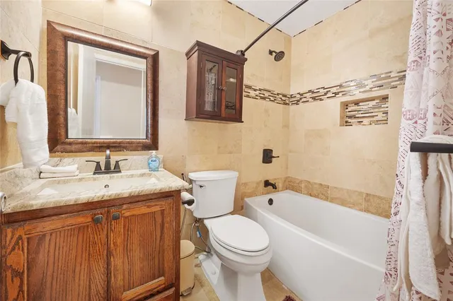 a bathroom with a granite countertop sink toilet mirror and bathtub