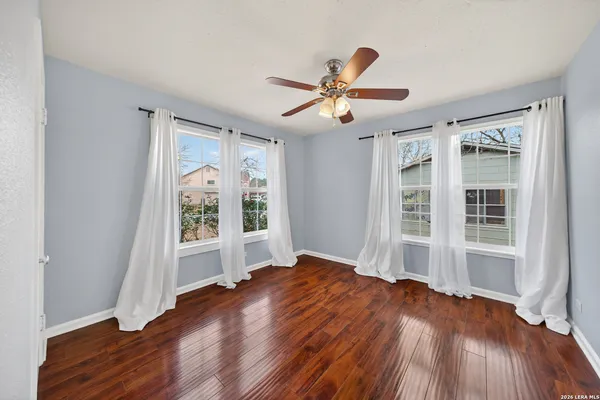 a view of empty room with wooden floor and fan