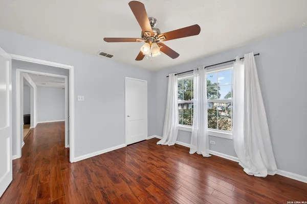 a view of empty room with wooden floor and fan