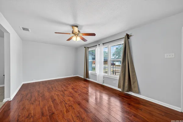 a view of an empty room with a window and wooden floor